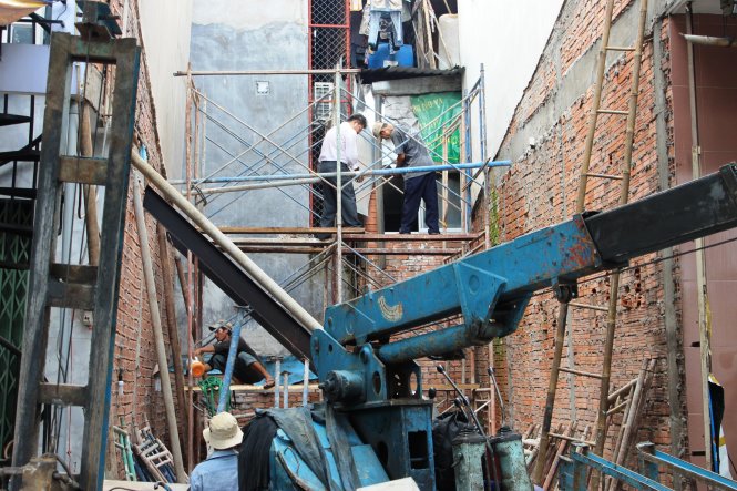 Công nhân đang tiếp tục gia cố căn nhà bị nghiêng - Ảnh: Hải Hiếu