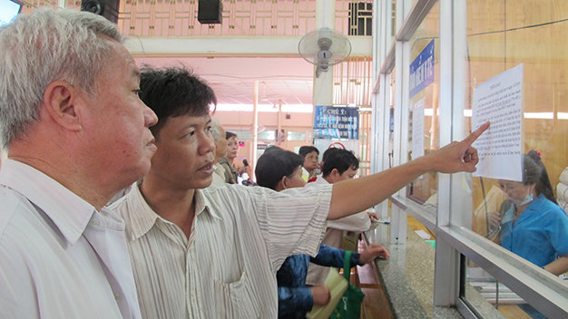 Người bệnh đọc quy định mới về bảo hiểm y tế tại Bệnh viện Ung bướu TP.HCM chiều 20-1 - Ảnh: Thùy Dương