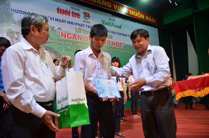 Phó TBT báo Tuổi Trẻ Tăng Hữu Phong (phải) và Phó GĐ Sở GD- ĐT Bình Định (trái) trao học bổng cho học sinh - Ảnh: Tr.Đăng
