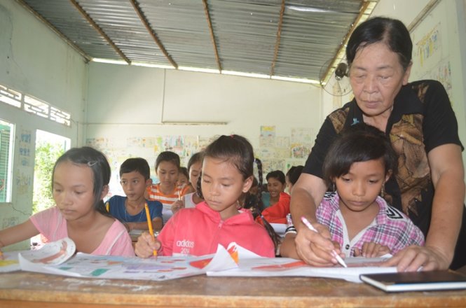 Bà Hai uốn nắn từng nét vẽ cho các em - Ảnh: Minh Tâm