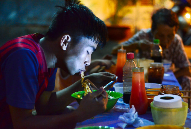 Chất béo chuyển hóa thường có trong khoai tây chiên, mì gói... Trong ảnh: người dân ăn mì gói tại một con hẻm ở Q.Bình Thạnh tối 17-6 Ảnh: THANH TÙNG