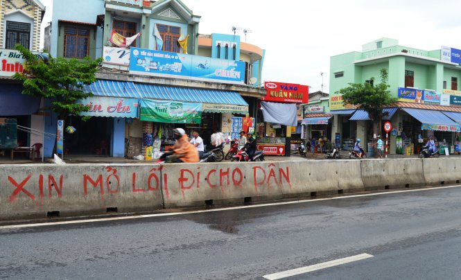 Người dân khu vực chợ Quán Gò, xã Bình An đã viết trên dải phân cách yêu cầu mở lối đi cho dân - Ảnh: LÊ TRUNG