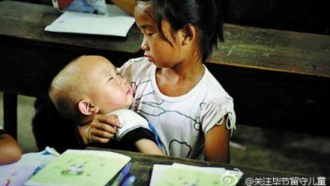 Một bé gái phải trông em do cha mẹ đi làm xa - Ảnh: Weibo