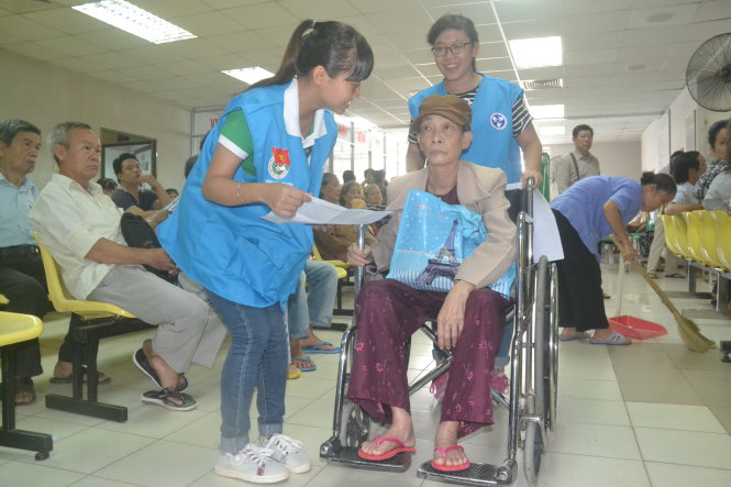 Tình nguyện viên đưa bệnh nhân đến khu vực khám chữa bệnh - Ảnh: Q.PHƯƠNG