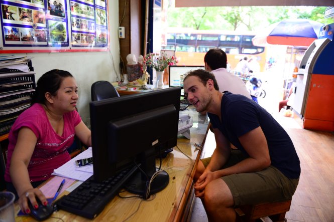 Du khách nước ngoài được hướng dẫn tra cứu thông tin du lịch tại một công ty du lịch ở TP.HCM - Ảnh: Thanh Tùng