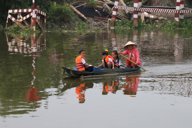 Bà Nguyễn Thị Hận chèo ghe đưa cháu tới trường ở bên kia sông - Ảnh: Yến Trinh