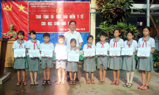 Thầy Hà Ngọc Hóa, hiệu trưởng Trường TH Bình Lợi, trao các suất BHYT cho học sinh nghèo - Ảnh: Hải Quân