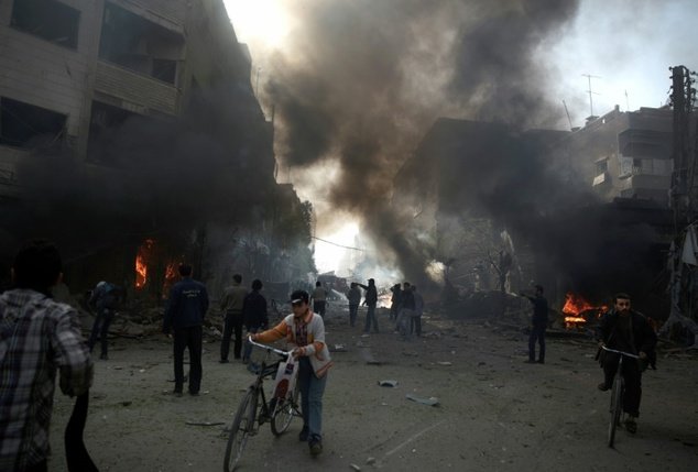 Người dân Syria tụ tập ở gần hiện trường một vụ không kích tại khu vực Douma do quân nổi dậy kiểm soát ở phía đông thủ đô Damascus - Ảnh: AFP