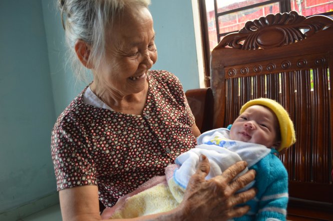 Bé Phạm Tấn Trung Kiên ngoan ngoãn trên tay cụ Dương Thị Nhớ - Ảnh: Tấn Lực