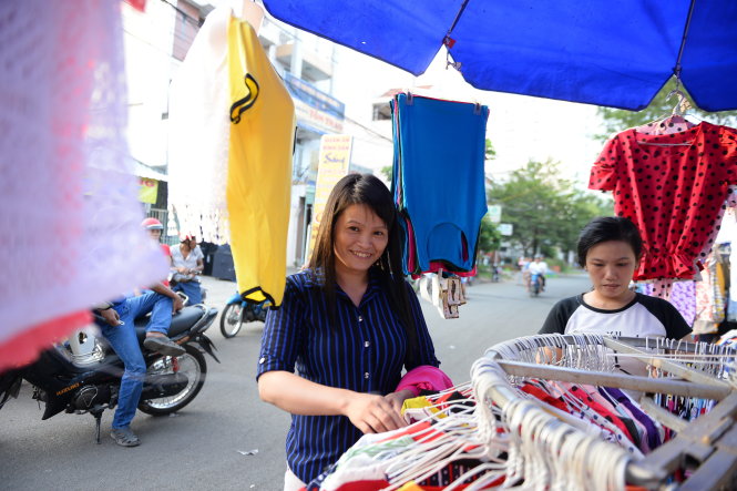 Chị Triệu Thị Hoa (trái, quê Thái Nguyên) - công nhân ở Khu công nghiệp Tân Tạo, Q.Bình Tân, TP.HCM - cho biết nghe nói công ty thưởng tết năm nay không bao nhiêu và chỉ thưởng cho những người gắn bó lâu năm. Vì mới đi làm được gần một năm nên chị không có trong danh sách thưởng tết phải đi phụ bán quần áo kiếm thêm tiền về quê ăn tết - Ảnh: Hữu Khoa