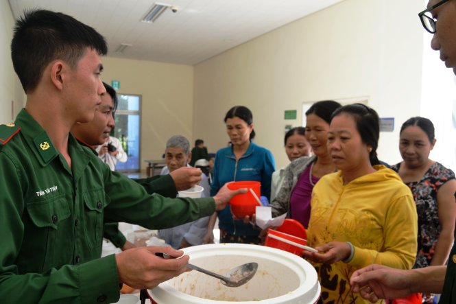 Các chiến sĩ đồn biên phòng cửa khẩu cảng Kỳ Hà phát những suất cháo cho bệnh nhân nghèo - Ảnh: Lê Trung