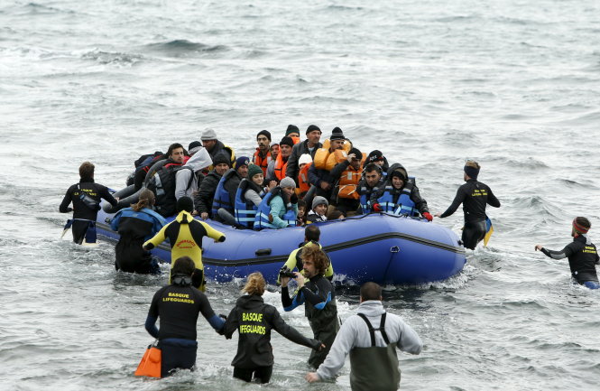 Người tình nguyện trên đảo Lesbos của Hi Lạp đón một chiếc thuyền phao chở người tị nạn - Ảnh: Reuters
