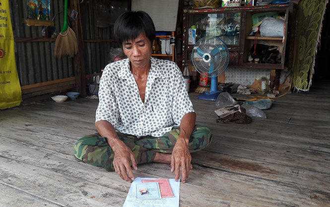 Ông Đực cầm sấp giấy tờ trên trên tay mà rầu rỉ không muốn ăn tết vì mất con - Ảnh: Bửu Đấu
