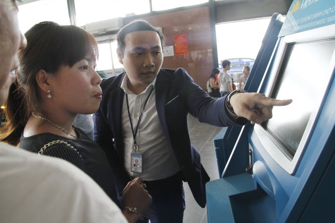 Nhân viên hướng dẫn hành khách làm thủ tục check-in trực tuyến tại các máy làm thủ tục tự động ở sân bay Nội Bài ngày 14-2-2016 - Ảnh: Nam Trần