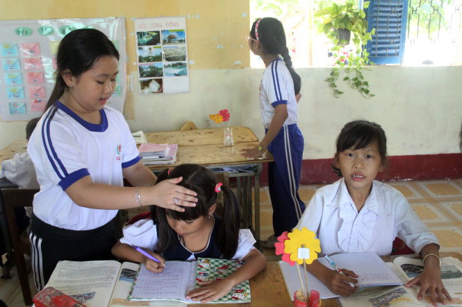 Em Lê Ngọc Như Ý điều chỉnh tư thế ngồi học đúng cho các bạn nhỏ Cần Giờ - Ảnh: Hải Quân