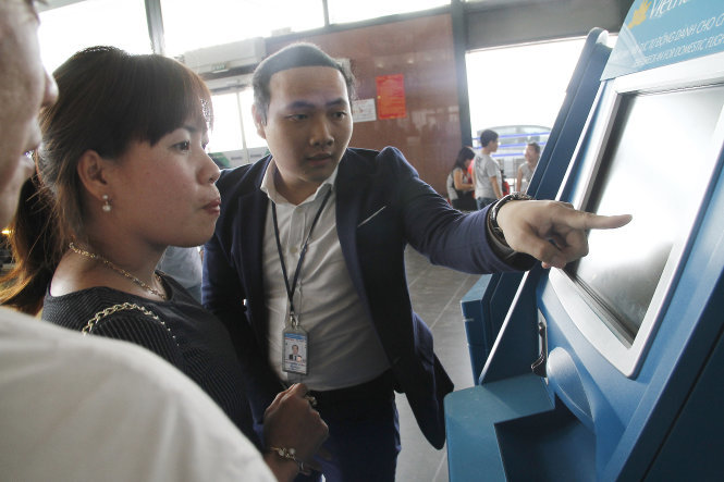 Nhân viên hướng dẫn hành khách làm thủ tục check-in trực tuyến tại các máy làm thủ tục tự động ở sân bay Nội Bài ngày 14-2-2016 - Ảnh: Nam Trần