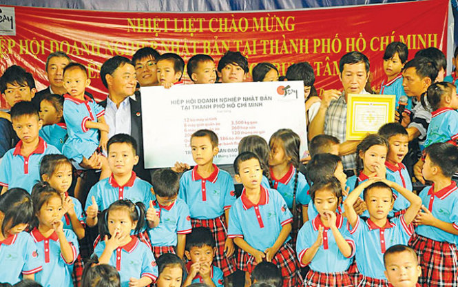 Ông Sakagami Tsutomu (người bế đứa trẻ) trao quà tặng cho Trung tâm nhân đạo Quê Hương - Ảnh: Khánh Ngọc