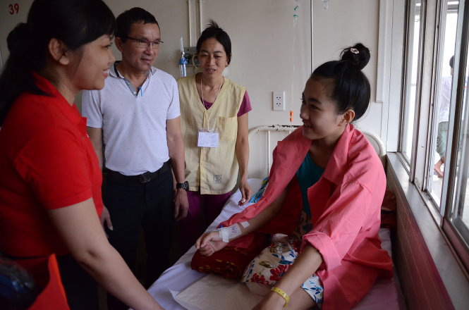 Đại diện báo Tuổi Trẻ (áo đỏ) và ông Lâm Tấn Lợi, giám đốc công ty võng xếp Duy Lợi (giữa), thăm nữ sinh Hà Vi - Ảnh: Vũ Thủy