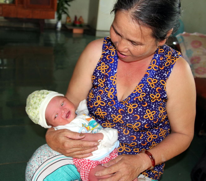 Bé sơ sinh bị bỏ rơi đang trong vòng tay của bà Lê Thị Tâm - Ảnh: Đức Trong