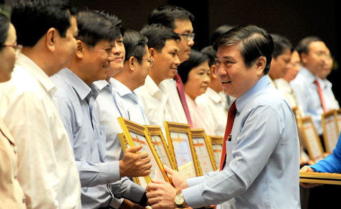 Ông Nguyễn Thành Phong, chủ tịch UBND TP.HCM, trao tặng bằng khen cho các đơn vị hoàn thành xuất sắc nhiệm vụ năm 2015 - Ảnh: Tự Trung