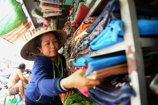 Chị Nguyễn Thị Kim Phượng sắp xếp lại hàng hóa trong tiệm lúc vắng khách ở chợ Thủ Đức, TP.HCM. Chị cho biết mấy năm gần đây buôn bán quá ế ẩm, từ sáng đến trưa chỉ có 1-2 khách đến mua hàng. Để duy trì cửa hàng và có tiền trang trải cuộc sống hằng ngày, chồng chị và con trai lớn phải đi làm thuê kiếm tiền - Ảnh: Hữu Khoa