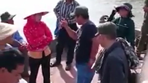 Khi bà Ngọc ngăn chặn ghe hút cát, nhiều người lạ mặt đe dọa bà Ngọc trước mặt lực lượng công an (ảnh cắt từ clip do gia đình bà Ngọc cung cấp quay vào tháng 9-2015). Bà Ngọc bị tạm giam vì bị cho rằng có hành vi chống người thi hành công vụ