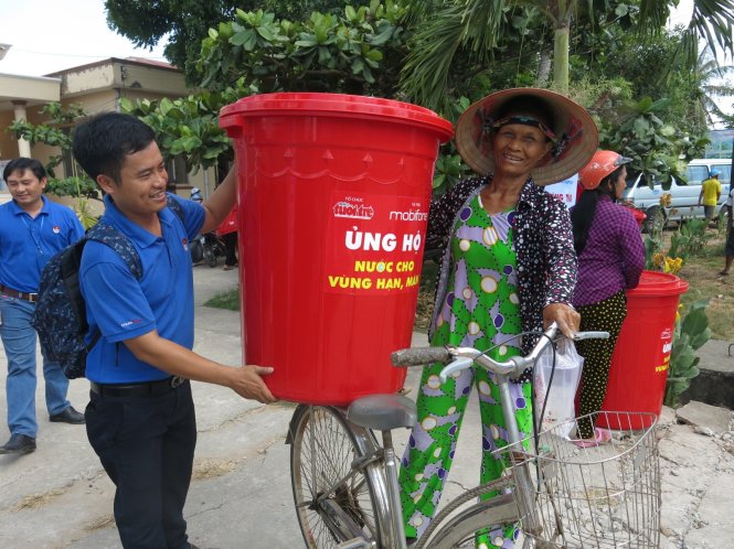 Đoàn viên thanh niên giúp đỡ đưa thùng chứa nước lên xe cho bà con - Ảnh: T.Trang