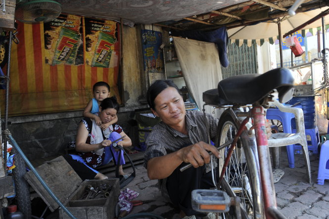 Vợ chồng anh Hà Văn Hồng và chị Âu Thị Mận phụ giúp nhau mưu sinh với nghề sửa chữa xe hơn 20 năm nay trên đường Phan Văn Hớn, Q.12, TP.HCM - Ảnh: Tự Trung