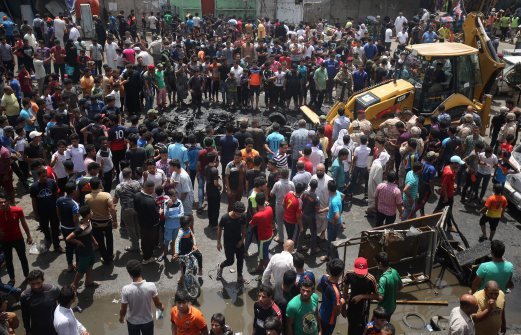 Người dân Iraq tụ tập quanh khu vực hiện trường đánh bom xe ở Sadr City, khu vực của người Shiite ở phía bắc thủ đô Baghdad ngày 11-5 - Ảnh: AFP