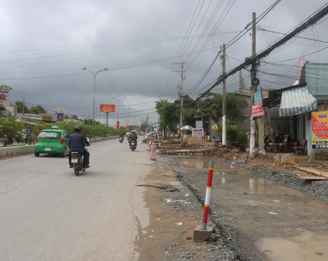 Trụ điện trên quốc lộ 91B chưa được di dời, ảnh hưởng đến tiến độ thi công nâng cấp, mở rộng đường - Ảnh: Lê Dân