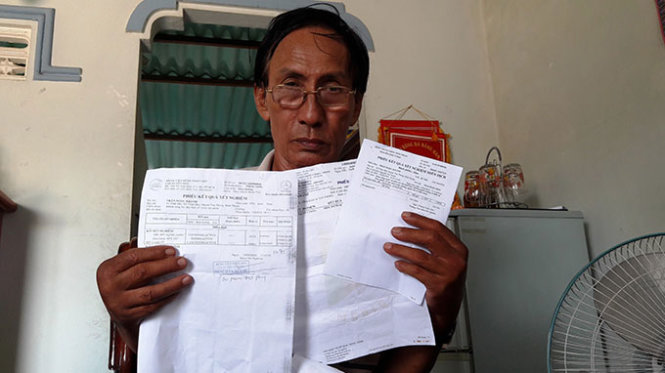 Ông Trần Ngọc Khanh cầm trên tay các kết quả xét nghiệm âm tính với HIV - Ảnh: Nguyễn Nam