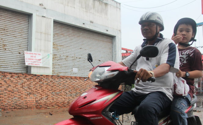 Một cửa hàng trên đường Kinh Dương Vương treo biển báo dời địa điểm kinh doanh do bức tường cao hơn 1m chắn hết cửa ra vào - Ảnh: Lê Phan