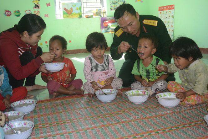 Thượng úy Dũng cùng chăm lo bữa ăn cho các cháu bé - Ảnh: T.Mai
