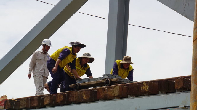 Khi vắng tàu, các công nhân tranh thủ di chuyển nguyên vật liệu để hoàn thiện các hạng mục quanh chân cầu - Ảnh: HÀ MI
