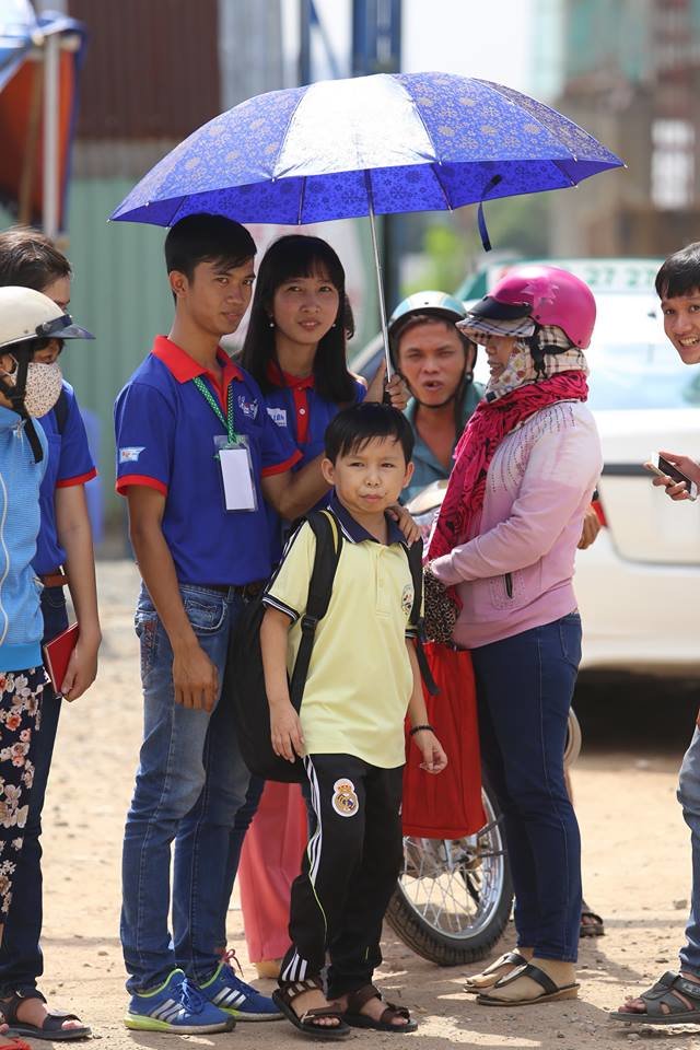 Thí sinh Võ Thành Nhân đang được các bạn sinh viên tình nguyện che nắng trong lúc chờ người nhà đó sau khi thi xong môn địa lý - Ảnh: NHƯ HÙNG