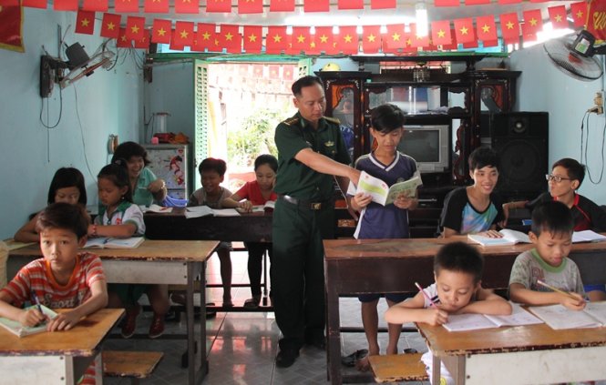 Đại úy Vũ Trường Tính hướng dẫn các em học bài - Ảnh: LÊ PHƯƠNG