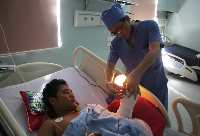 Bác sĩ theo dõi sức khỏe của anh Anh chiều 11-7 sau ca phẫu thuật nối bàn tay phức tạp - Ảnh: DOÃN HÒA