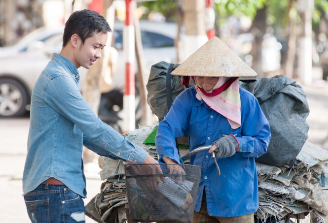 Bạn Nguyễn Minh Tuấn, thành viên quỹ bánh mì từ thiện 37, trao bánh mì cho chị nhặt ve chai - Ảnh: D.HÒA
