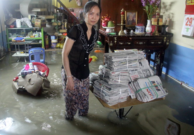Chị Lê Hoàng Trang Châu thu dọn đồ đạc trong căn nhà ngập nước sau cơn mưa ngày 23-7 - Ảnh: Q.KHẢI