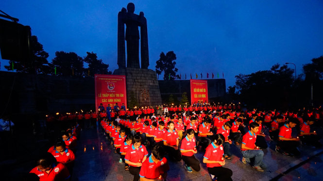 Đoàn viên, thanh niên cầm nến làm lễ trước tượng đài trong buổi thắp nến tri ân tại Nghĩa trang liệt sĩ TP.HCM tối 26-7 - Ảnh: QUANG ĐỊNH