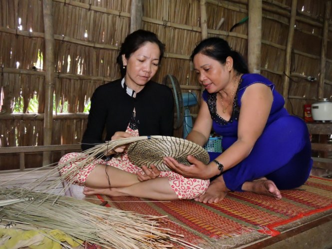 Bà Pha (phải) hướng dẫn một hội viên phụ nữ nghèo trong xóm làm hàng thủ công để cải thiện cuộc sống - Ảnh: THÚY HẰNG