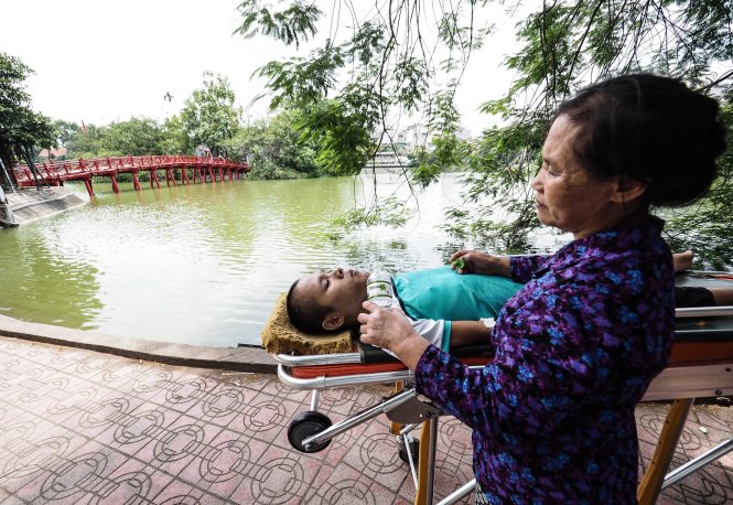 Phạm Sỹ Long, người có đơn đề nghị được ghép đầu, được mẹ đưa ra hồ Gươm chơi sáng 10-8 - Ảnh: NGUYỄN KHÁNH