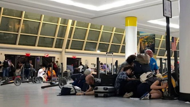 Hành khách ở Cổng số 1 (Terminal One) tìm chỗ trú ẩn khi có cảnh báo về tiếng súng tại sân bay JFK ngày 14-8 (giờ địa phương) - Ảnh: AFP