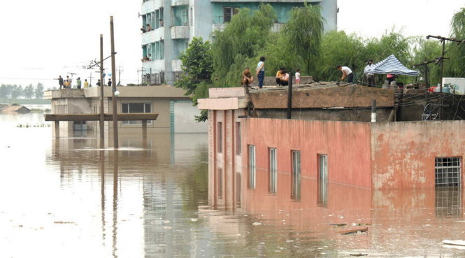 Người dân leo lên mái nhà tránh lũ trong đợt lũ năm 2012 ở Triều Tiên - Ảnh: REUTERS/KCNA