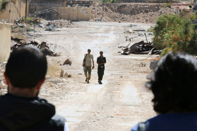 Quân nổi dậy Syria đi ngang các tòa nhà bị hư hại gần đường Castello ở Aleppo ngày 16-9 - ảnh: Reuters