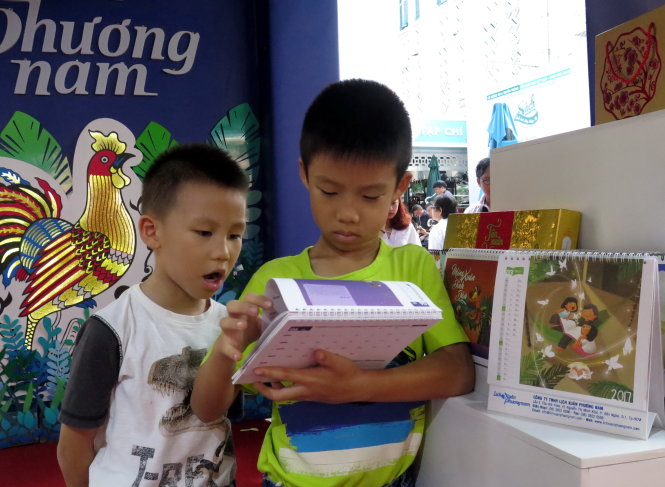 Hai anh em Thiên Khải và Khải Anh (Q.7) thích thú xem mẫu lịch khuyến đọc Chắp cánh ước mơ - Ảnh: L.ĐIỀN
