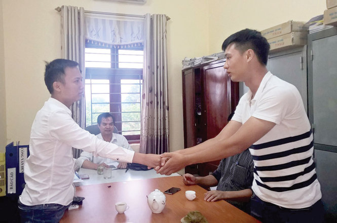 Ông Ngô Quang Hưng (phải) bắt tay và xin lỗi phóng viên Trần Quang Thế tại trụ sở Công an xã Vĩnh Ngọc, huyện Đông Anh, Hà Nội chiều 24-9 - Ảnh: K.H.