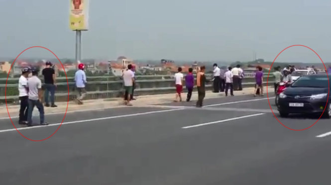 Trong vụ việc xảy ra trên cầu Nhật Tân ngày 23-9, từ vị trí những người ngăn cản nhà báo tác nghiệp (bìa trái) đến vị trí chiếc taxi có tài xế tự tử (bìa phải) còn có rất đông người, không rõ vị trí nào là ranh giới hiện trường vụ việc - Ảnh cắt từ clip