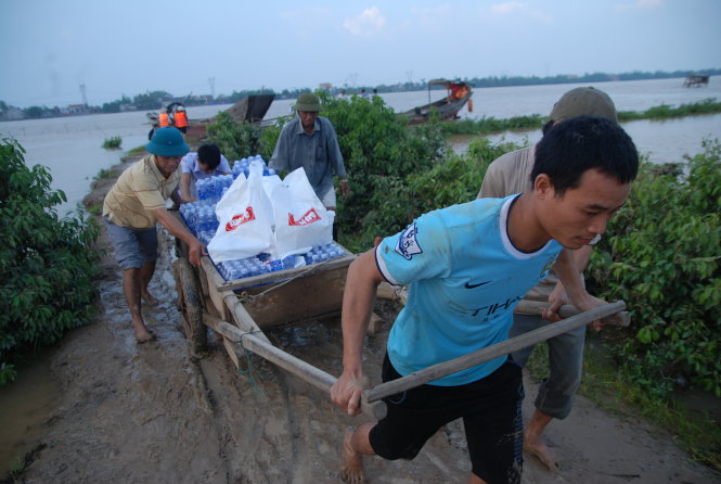 Người dân vùng Cồn Nâm, cồn nổi nằm tách biệt giữa sông Gianh (thị xã Ba Đồn, Quảng Bình), mang xe kéo ra mép sông kéo hàng cứu trợ của bạn đọc báo Tuổi Trẻ Ảnh: QUỐC NAM
