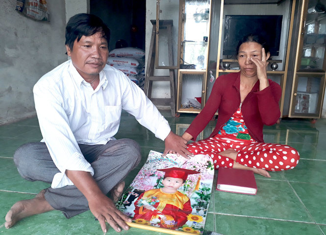 Vợ chồng chị Hạnh và anh Tuấn bên bức hình bé Hậu và bức xúc vì cách giải quyết của trường Mẫu Giáo Tân Lập mỗi khi nhắc đến đứa con - Ảnh: BỬU ĐẤU